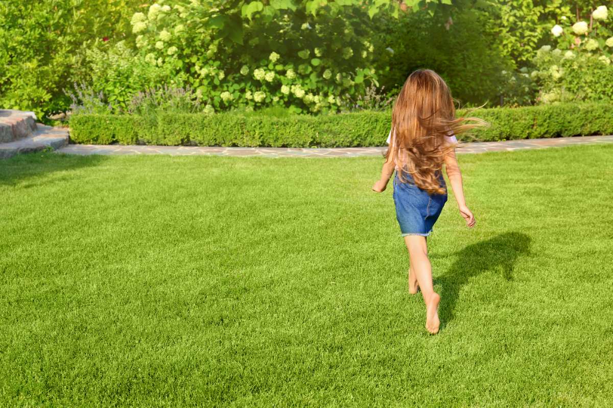 Cute little girl running in green park on summer day