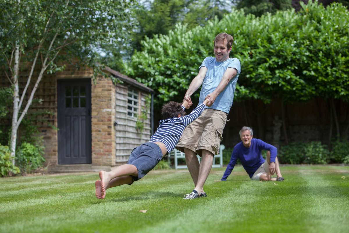 Three generation family fooling around in garden