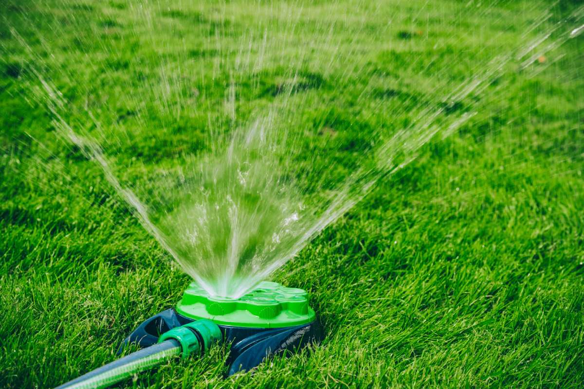 Sprinkler System Watering a Lush Green Lawn in Bright Sunshine on a Clear Day